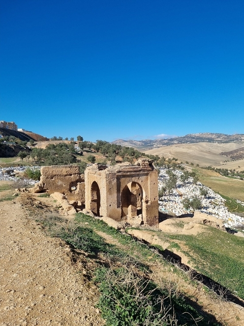Ruins overlooking a cemetery and rolling hills.