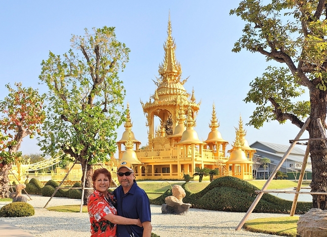       Couple posing in front of a golden temple.
  