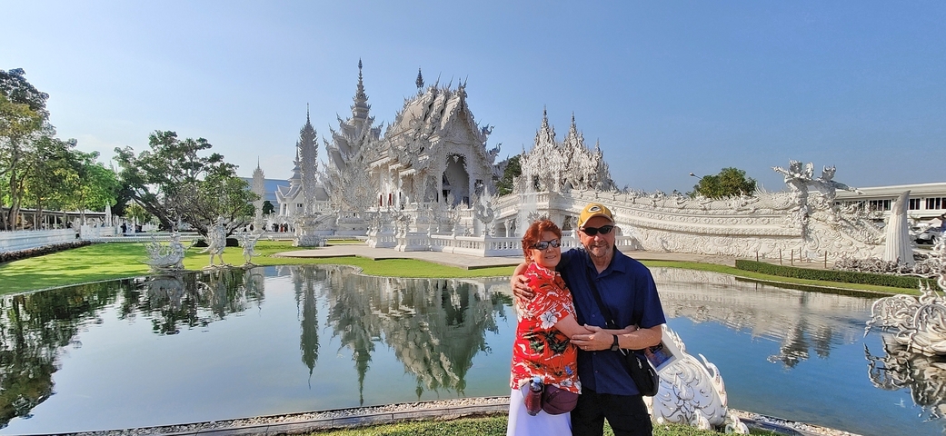       Couple in front of a white temple with reflection in water.
  