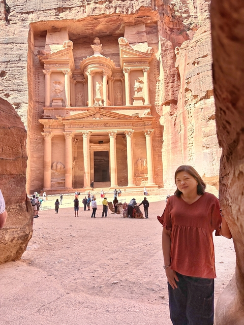 Woman standing in front of the iconic Treasury facade in Petra.