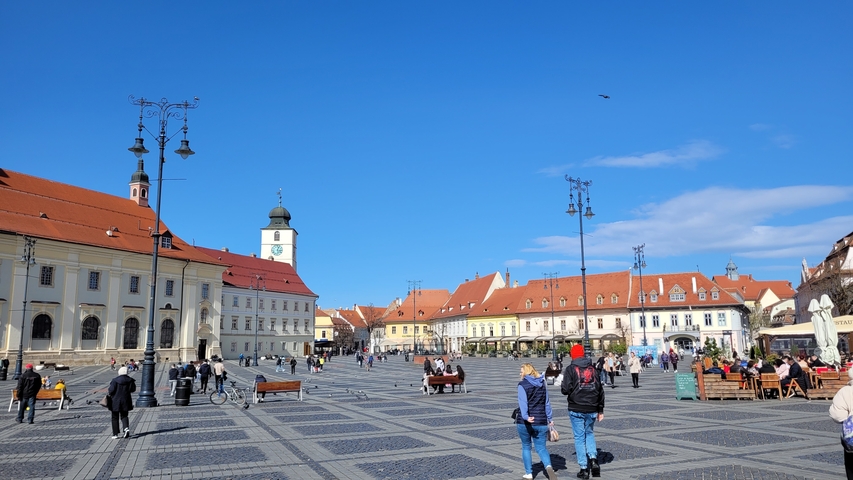 Busy public square with historical buildings and people enjoying the day.
