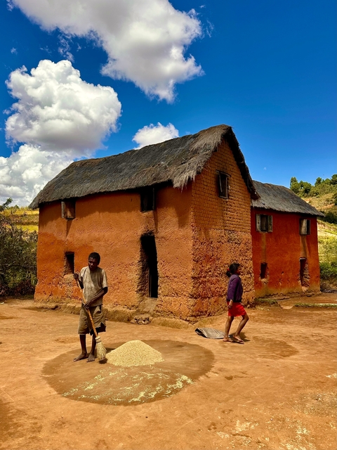       Traditional home with people passing by in a rural setting.
  