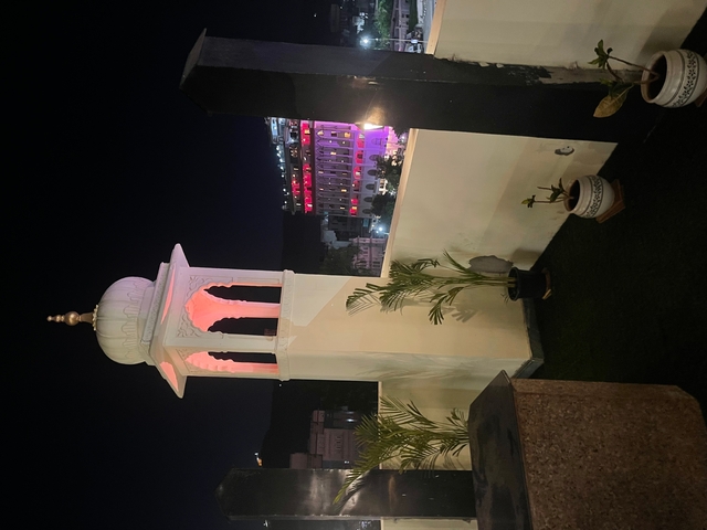 Rooftop view of a minaret with colorful lights at night.