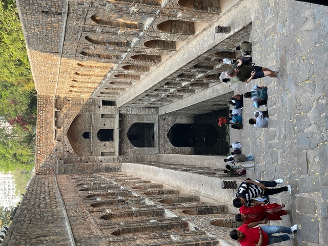 Visitors standing near a stepped structure at an ancient site.