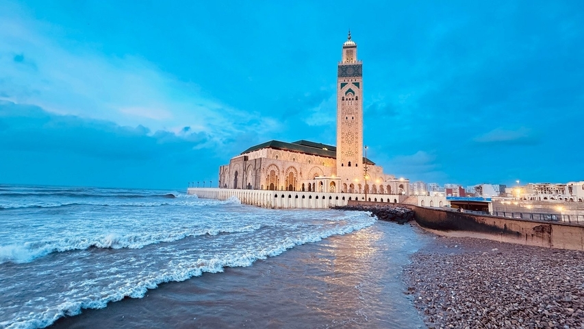       Coastal mosque with waves crashing during blue hour.
  