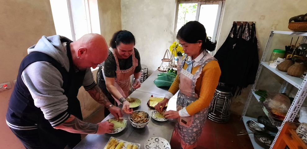       Three people preparing food inside a house.
  