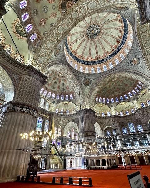 Interior of an ornately decorated mosque with stained glass.