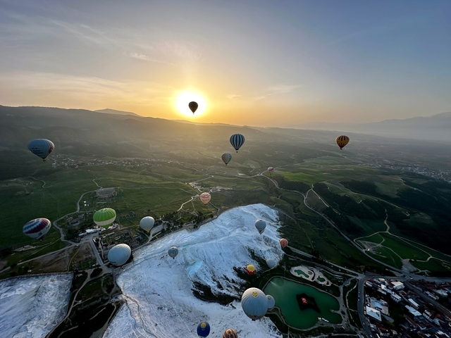 Hot air balloons over Pamukkale at sunrise.