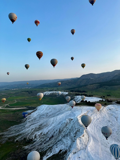 View of hot air balloons over a rocky landscape.