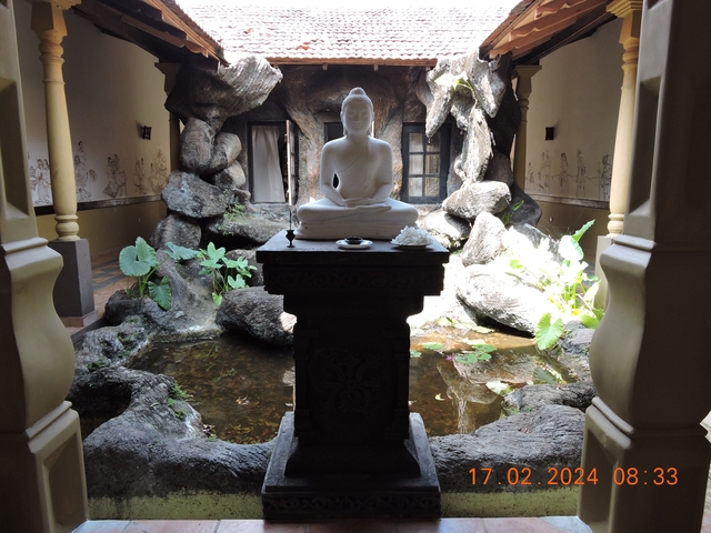 Statue of a meditating Buddha surrounded by a garden setting