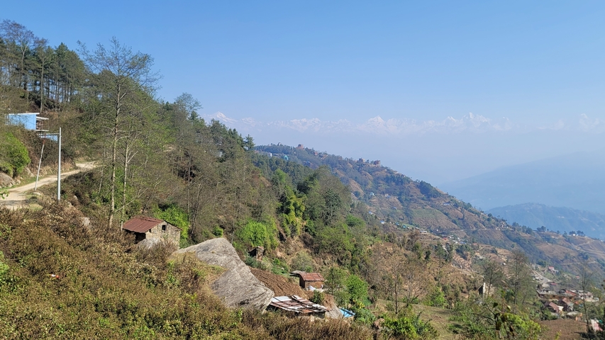 Hills with residential structures and a mountain backdrop.