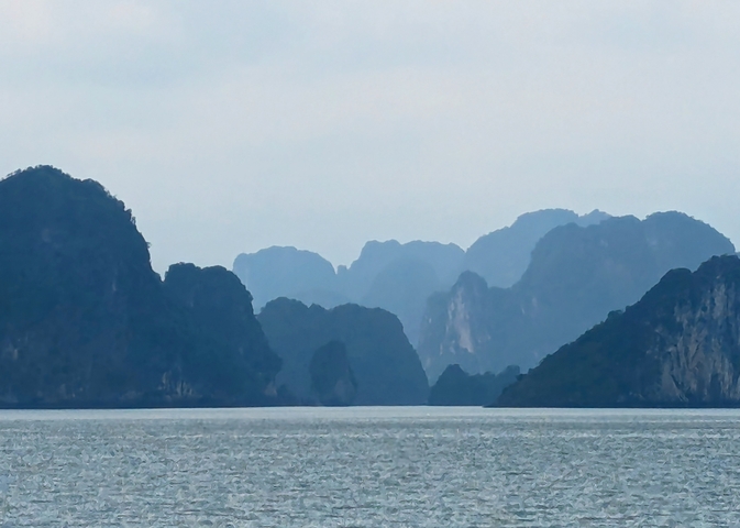       Karst mountains rising from the water under a cloudy sky.
  