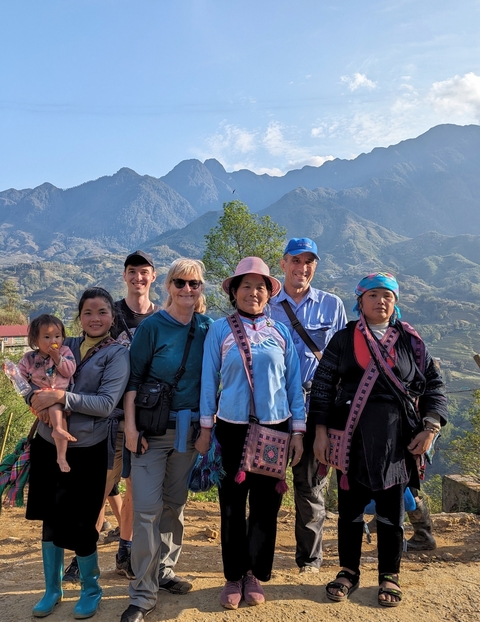       Group of people in traditional and casual clothing with a scenic mountain backdrop.
  