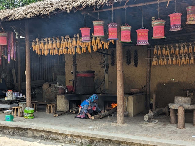       Traditional kitchen with a woman cooking on an open fire.
  