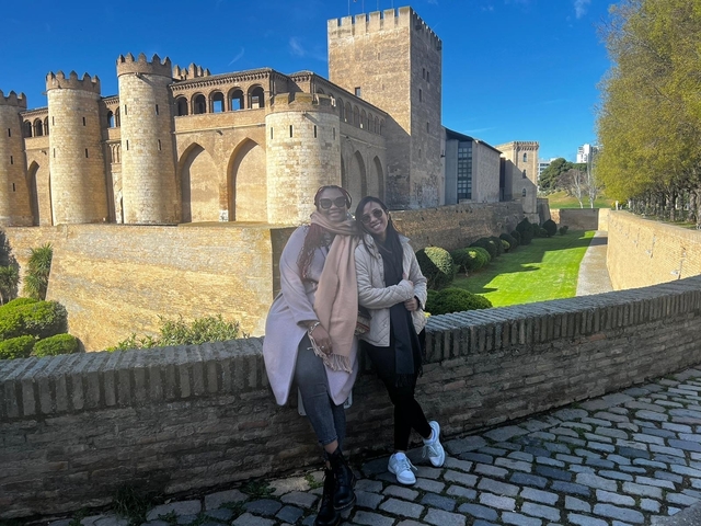 Two women posing in front of a historic building.