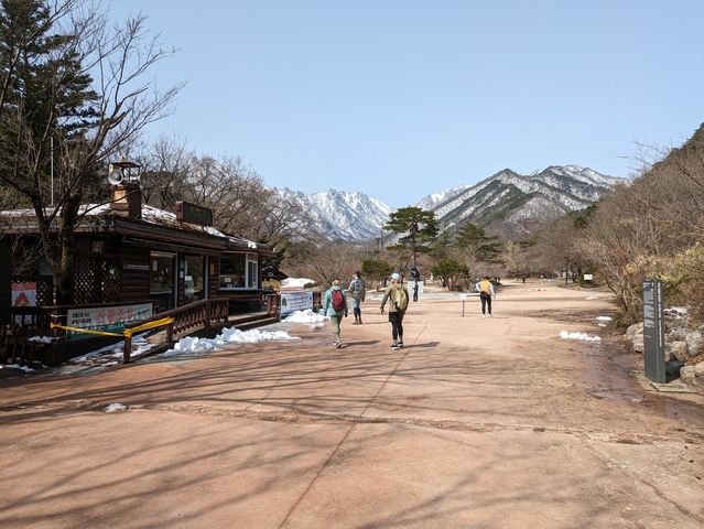 People walking along a path with snowy mountains.
