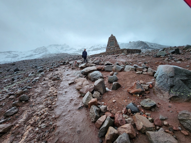       Person on a rocky path in a snowy mountainous area.
  