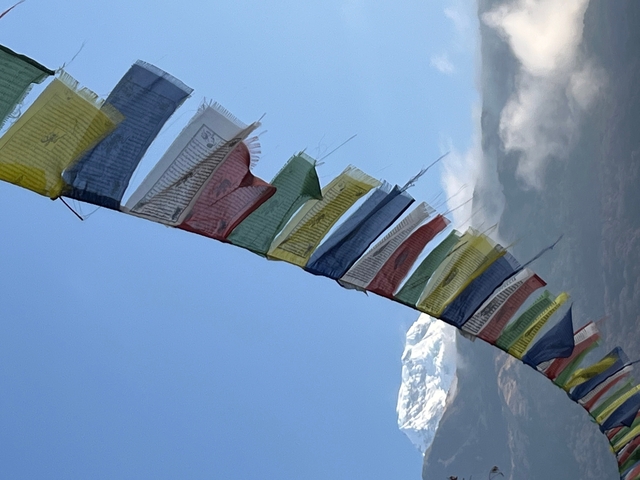 Prayer flags with a snowy mountain in the background.