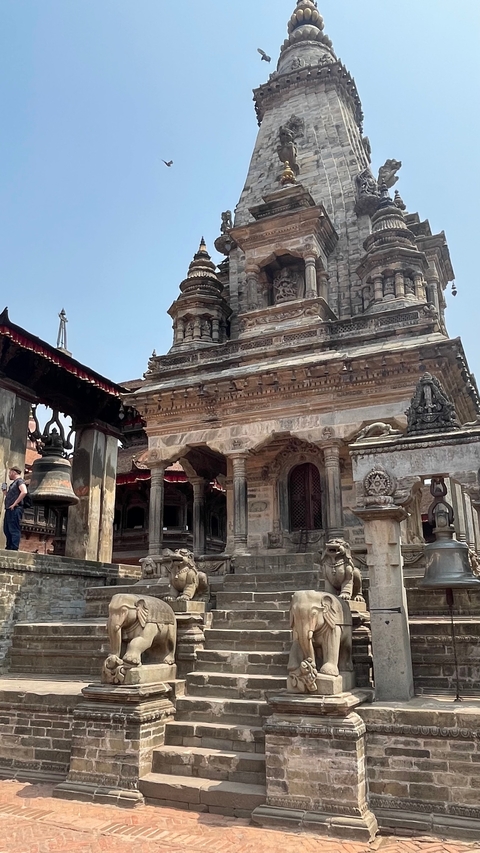       Temple with detailed carvings and a large bell.
  