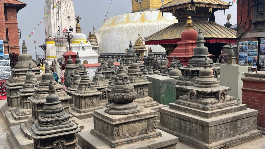 Group of small stupas with a large stupa in the background.