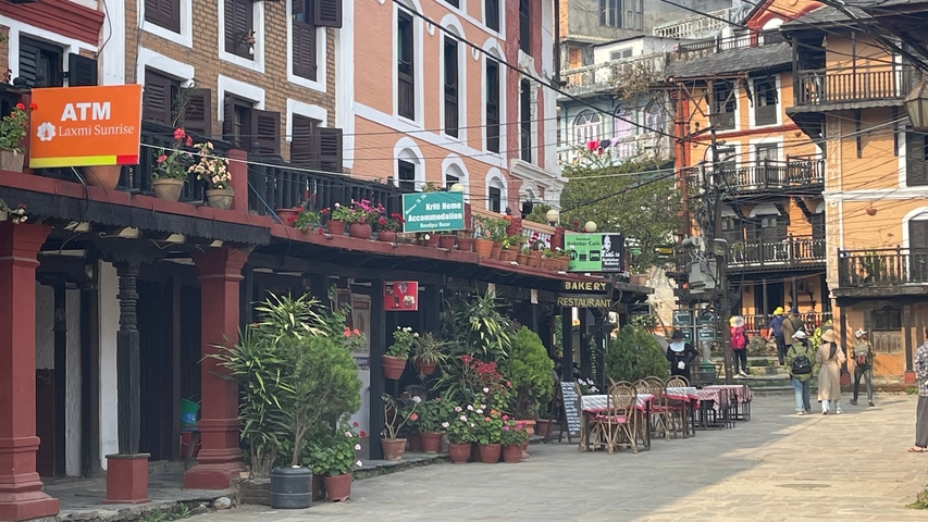       Street view with signs, plants, and a restaurant.
  
