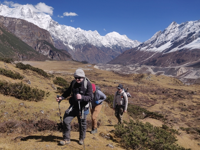 Hikers on a mountain trail with snowcapped peaks