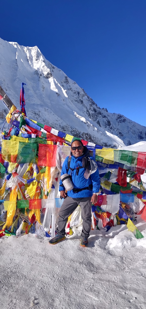 Person posing with prayer flags in a snowy setting