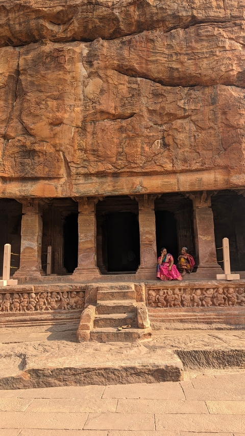       Two women sitting on temple steps, dressed in traditional clothing.
  