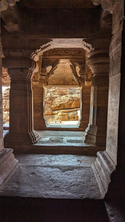       Rocky view through temple columns towards a natural landscape.
  