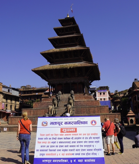       A traditional building with statues on steps in front of it.
  