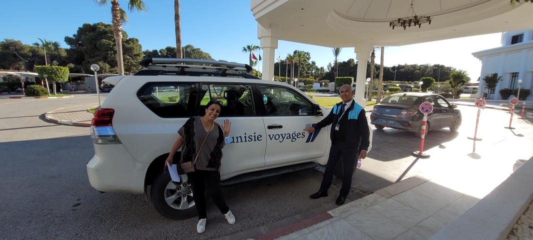       Two people posing in front of a vehicle labeled 'Tunisie Voyages'.
  