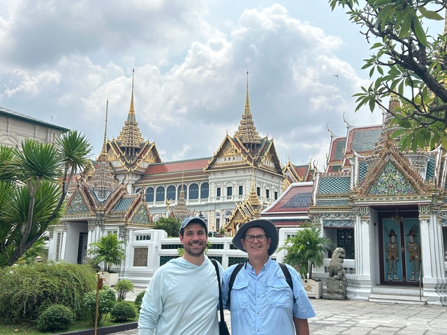 Two men standing in front of ornate palace buildings.
