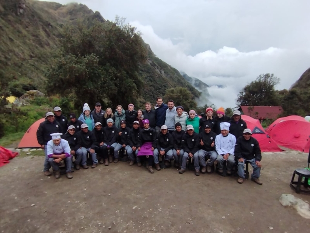       Large group of hikers and guides posing in a mountainous area.
  