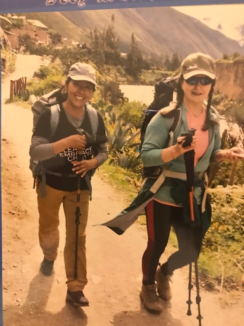       Two people hiking with trekking poles on a trail.
  