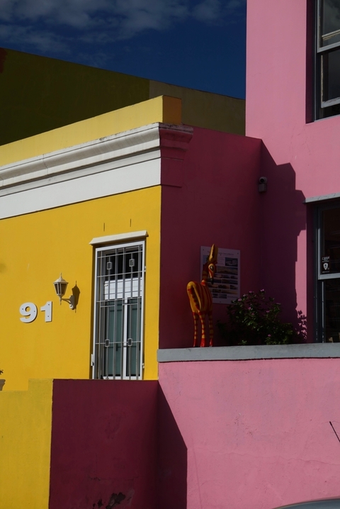 A vibrant yellow and pink building with modern architectural features and street art.
