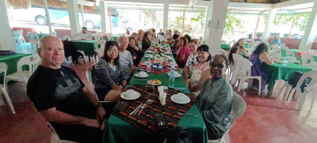 Group of people seated at a long table having a meal indoors.