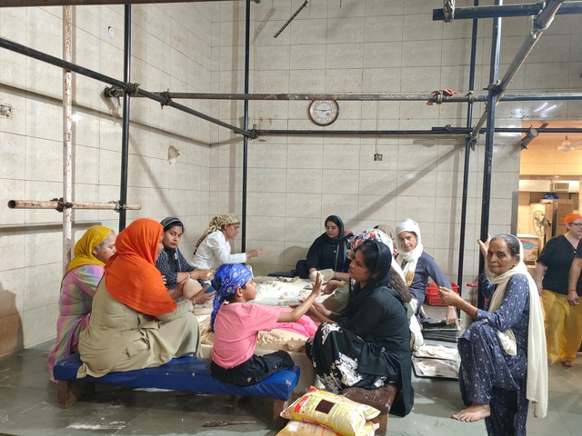 Group of women engaged in cooking activity inside a kitchen area.