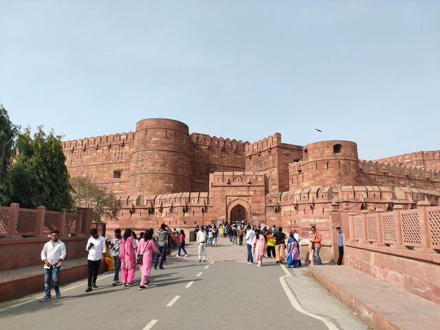 People walking towards a large red fort.