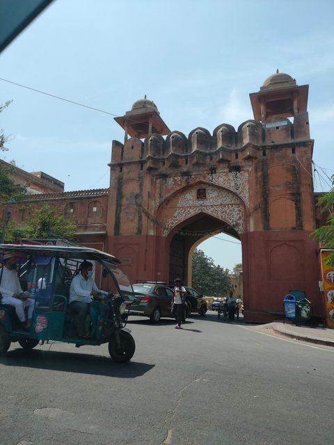 People and vehicles at an entrance gate with intricate patterns.