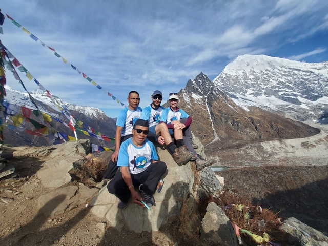 Group of hikers posing with mountain peaks in the background.