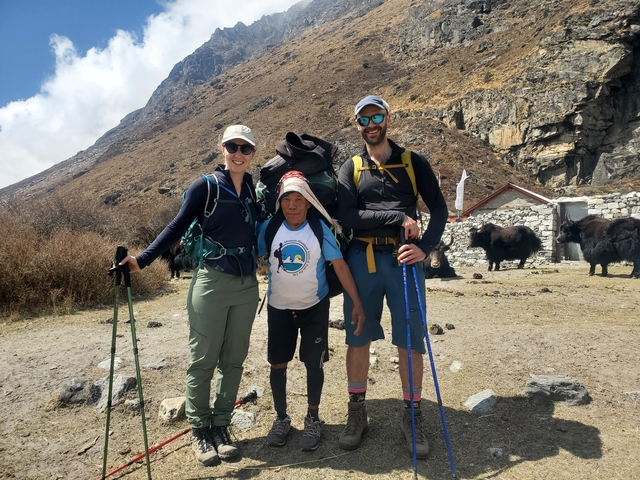 Hikers with yaks and mountain scenery.