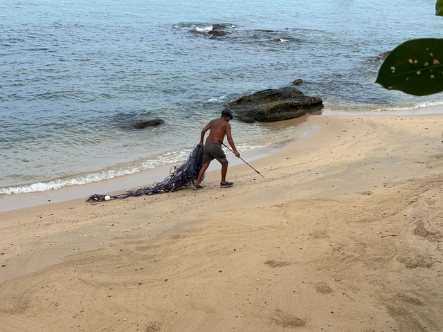 Man cleaning a beach with a net.