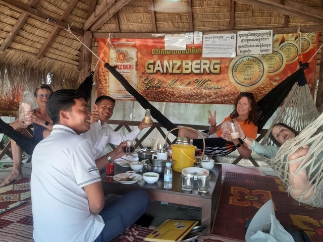Group of people enjoying food and drinks in a casual setting with a banner.