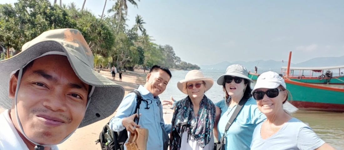 Group of people enjoying a day at the beach with palm trees and a boat.