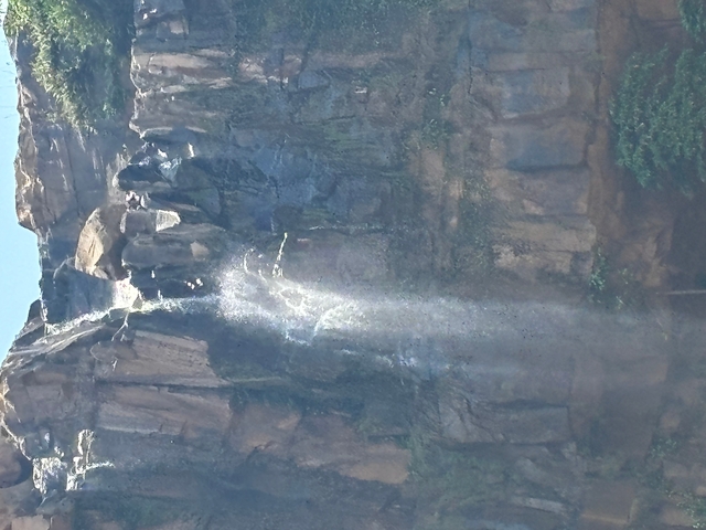 Waterfall flowing down a cliff with surrounding rocks.
