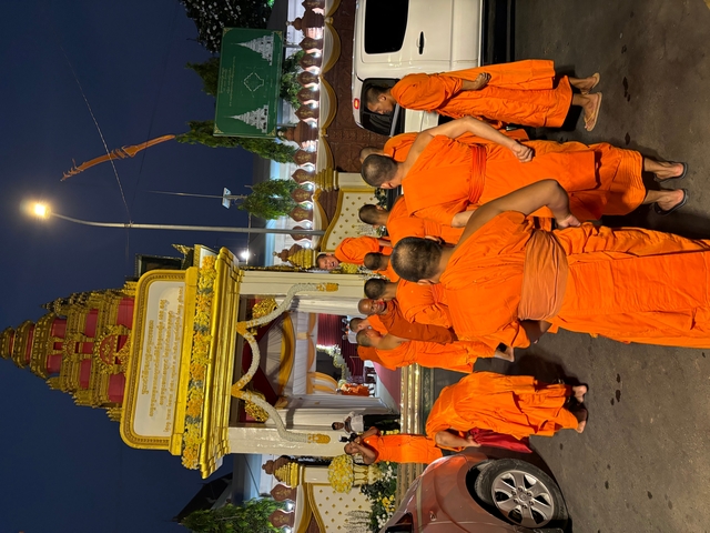       Monks in orange robes gathering outside a temple.
  