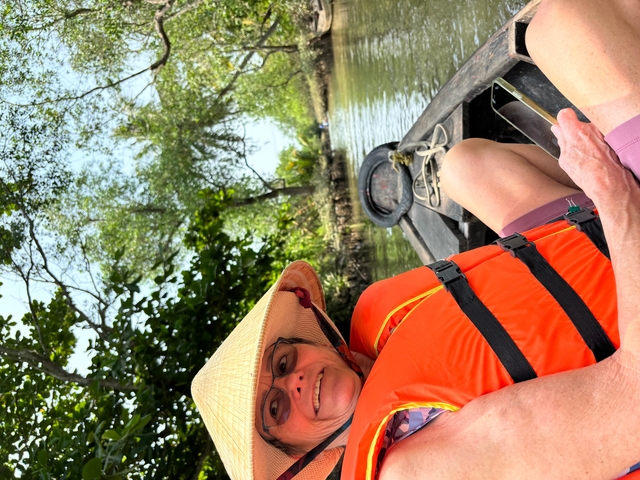 Person in life vest sitting in a boat on a river tour.
