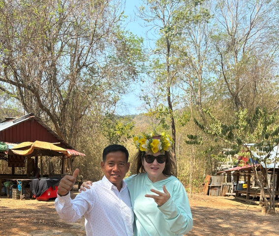       Two people posing in a rural setting among trees.
  