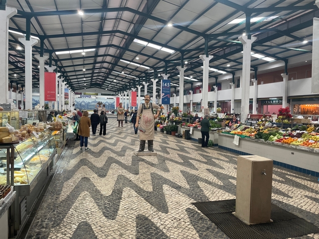 Indoor market with various stalls and a statue.