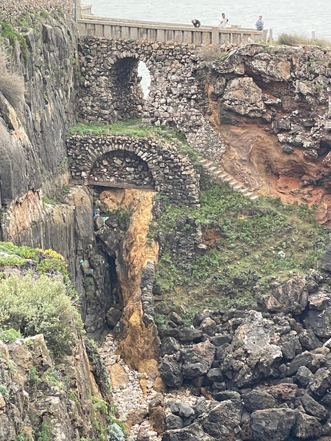       Ancient stone archway and stairs in a rocky terrain.
  